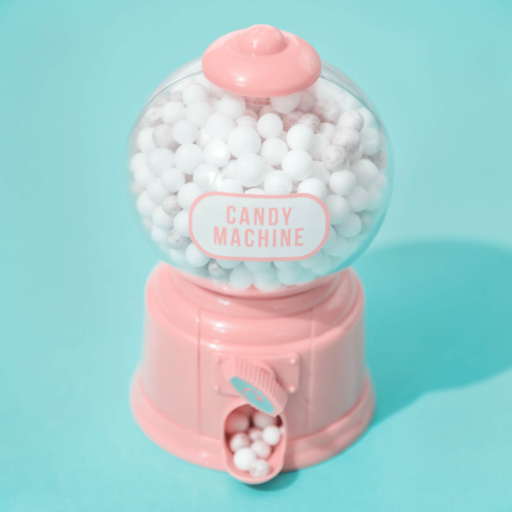 Mini pink gumball machine on a light blue background.