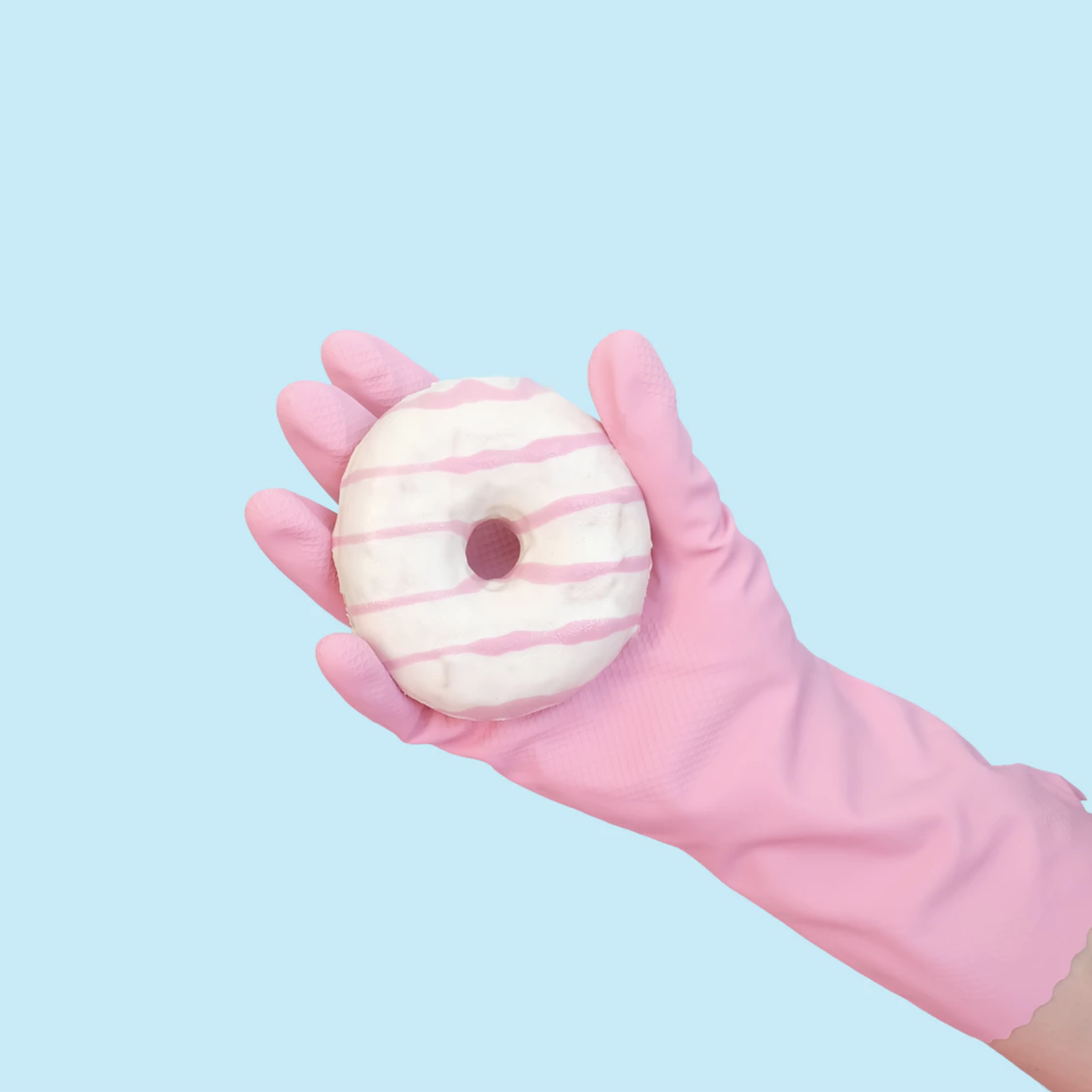 A glazed donut held by a hand in a rubber glove on a light blue background.