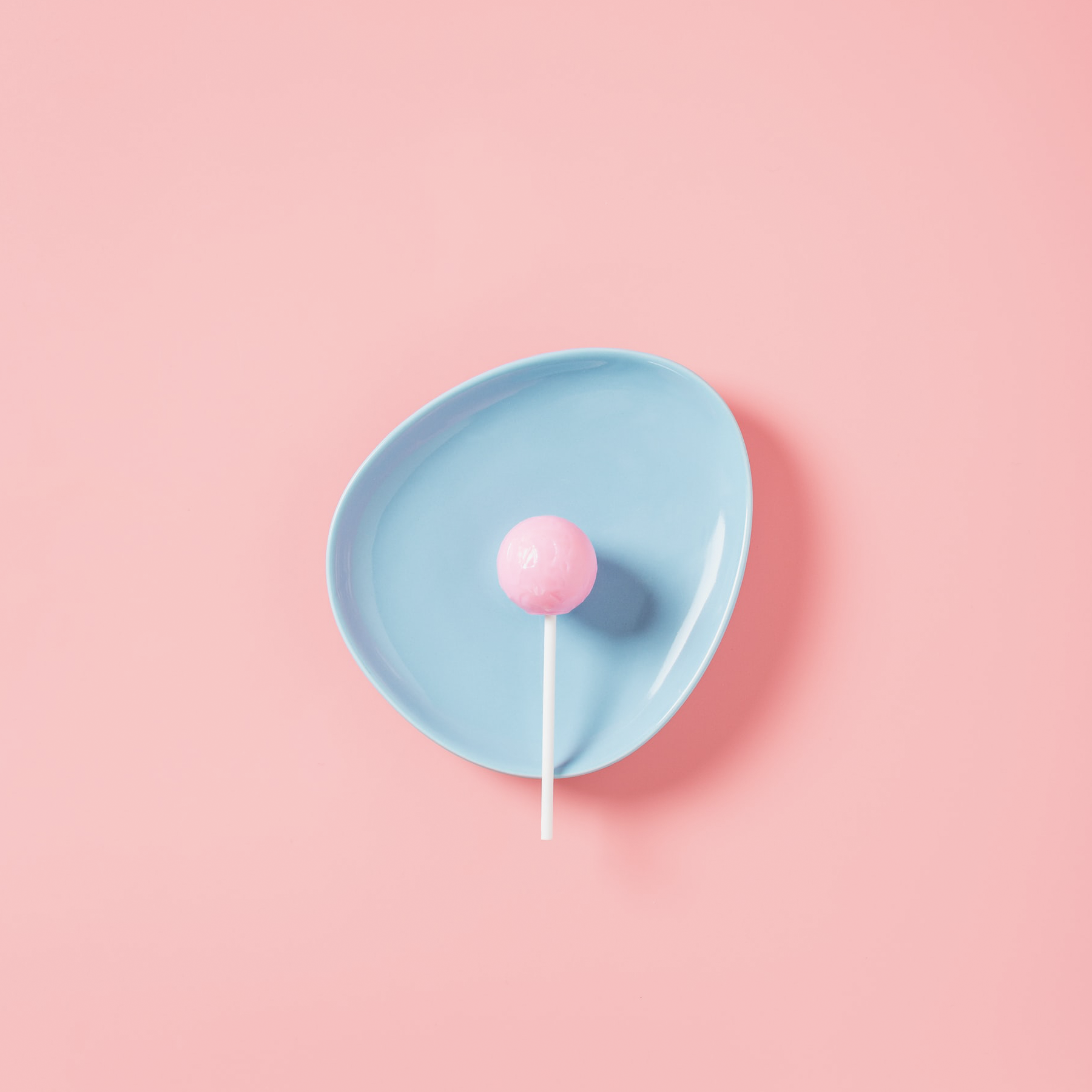 A pink lollipop on a blue plate.
